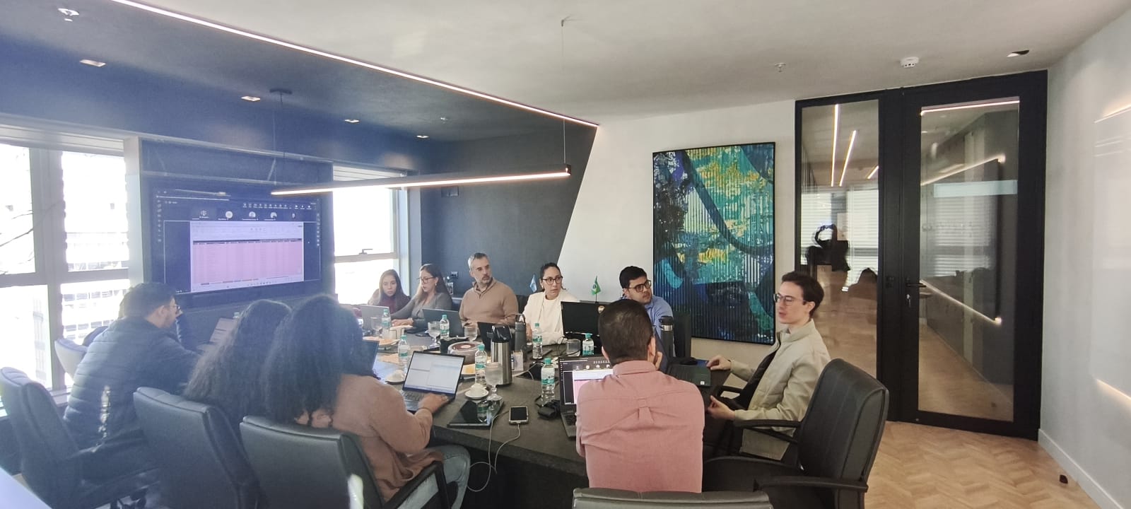 Turma de treinamento in-company acompanhando uma planilha projetada na sala de reunião do cliente